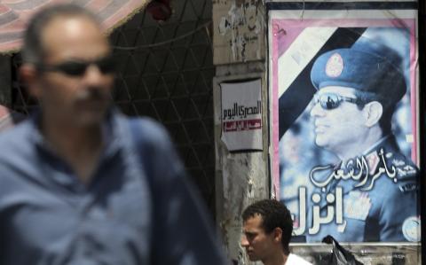 People walk in front of an election campaign poster of presidential candidate and Egypt's former army chief Abdel Fattah al-Sisi, along a highway in downtown Cairo