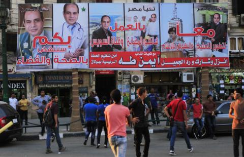 People walk under an election campaign billboard of presidential candidate and former army chief Abdel Fattah al-Sisi a day ahead of presidential elections at Talaat Harab Square in Cairo