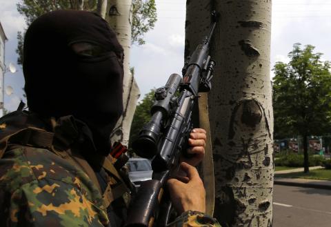 A pro-Russian rebel sniper of the Battalion Vostok takes cover behind a tree near the local administration building in the eastern Ukrainian city of Donetsk