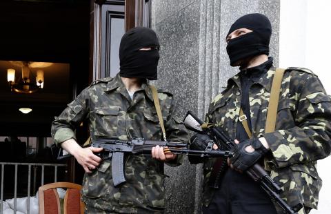 Pro-Russian armed men stand at the entrance to the regional government headquarters in Luhansk, eastern Ukraine