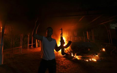 A protester reacts as the U.S. Consulate in Benghazi is seen in flames during a protest by an armed group said to have been protesting a film being produced in the United States