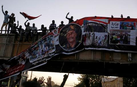 Protesters tear down a banner with a picture of Sudan's head of transitional council, Lieutenant General Abdel Fattah Al-Burhan Abdelrahman and pictures of Sudanese soldiers and protesters together, minutes after it was hanged to a railroad bridge near the Defence Ministry in Khartoum, Sudan, April 20, 2019. PHOTO BY REUTERS/Umit Bektas