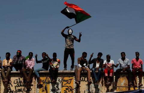 A Sudanese protester wearing a Guy Fawkes mask waves a national flag outside the defence ministry compound in Khartoum, Sudan, April 24, 2019. PHOTO BY REUTERS/Umit Bektas