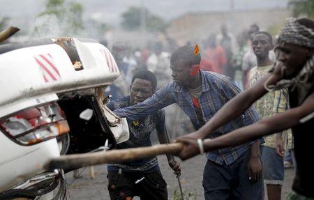 Protesters destroy a car belonging to a policeman after they intercepted him at a barricade during demonstrations against the ruling CNDD-FDD party's decision to allow President Pierre Nkurunziza to run for a third five-year term in office, in Bujumbura, Burundi April 30, 2015. PHOTO BY REUTERS/Thomas Mukoya