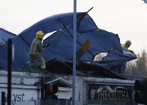 Rescue workers cover the wreckage of a police helicopter which crashed onto the roof of the Clutha Vaults pub in Glasgow, Scotland