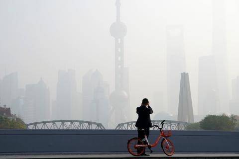 A man takes picture on a bridge in front of the financial district of Pudong covered in smog during a polluted day in Shanghai, China, November 28, 2018. PHOTO BY REUTERS/Aly Song