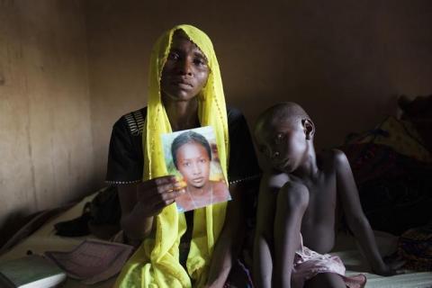 Rachel Daniel, 35, holds up a picture of her abducted daughter Rose Daniel, 17, as her son Bukar, 7, sits beside her at her home in Maiduguri, May 21, 2014. PHOTO BY REUTERS/Joe Penney