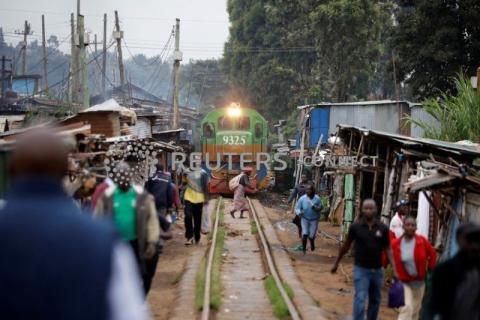 A woman crosses a railway track just as a train approaches a makeshift train station in the Kibera slum of Nairobi, Kenya, November 29, 2019. PHOTO BY REUTERS/Baz Ratner