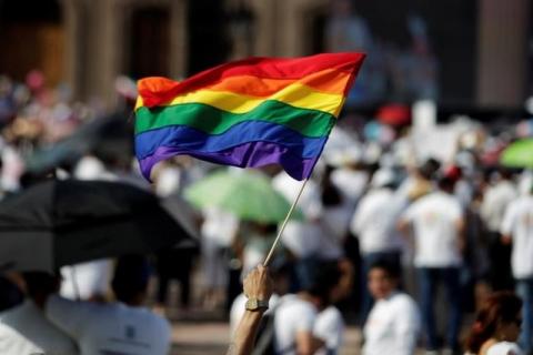 A man holds up the rainbow flag towards thousands of catholics and conservatives gathered together against the legalization of gay marriage and to defend their interpretation of traditional family values in Monterrey City, Mexico, September 10, 2016. PHOTO BY REUTERS/Daniel Becerril