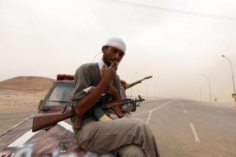 A rebel fighter from the city of Misrata smokes a cigarette as he stands guard on the road to the airport in the southern Libyan city of Sabha