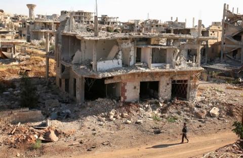 A rebel fighter walks past damaged buildings in a rebel-held part of the southern city of Deraa, Syria, June 22, 2017. PHOTO BY REUTERS/Alaa Al-Faqir