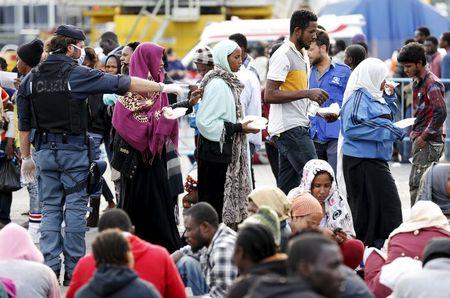 Migrants rest after disembarking from the British assault ship HMS Bulwark at the Sicilian port of Catania after being rescued at sea, Italy, June 8, 2015. PHOTO BY REUTERS/Antonio Parrinello