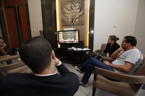 Reporters watch a live feed of Libyan members of parliament meeting to decide on the new prime minister at the parliament in Tripoli