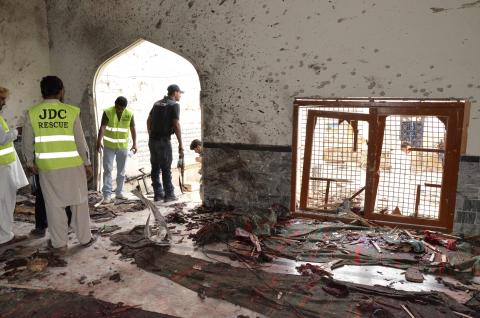 Rescue workers and a policeman stand at the site of an explosion in a Shi'ite mosque in Shikarpur, located in Pakistan's Sindh province, January 30, 2015. PHOTO BY REUTERS/Amir Hussain