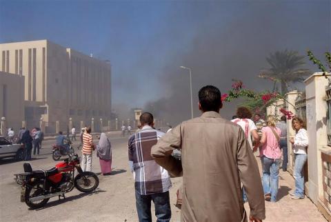 Residents and tourists watch as smoke raises near a state security building after a blast in South Sinai