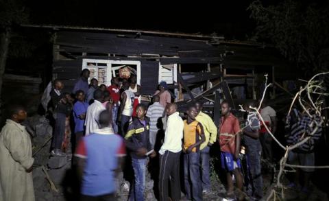 Residents gather at the ruins of a house struck by a mortar bomb during an operation in Goma town