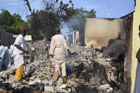 Residents watch as two men walk amidst rubble after Boko Haram militants raided the town of Benisheik, west of Borno State capital Maiduguri