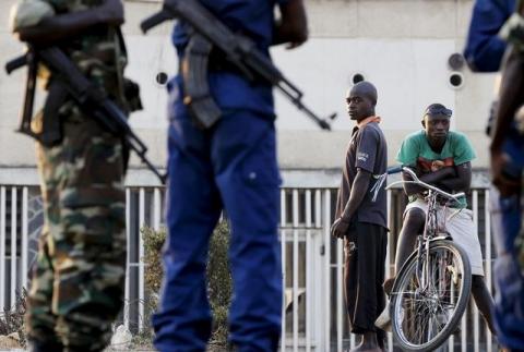 Residents look on as police and soldiers guard a voting station in Burundi's capital Bujumbura during the country's presidential elections, July 21, 2015. PHOTO BY REUTERS/Mike Hutchings