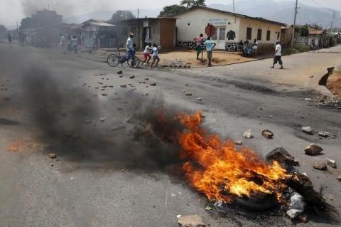 Residents move past a burning barricade on a rock strewn street in Bujumbura's Niyakabiga district on Presidential election day in Burundi, July 21, 2015. PHOTO BY REUTERS/Mike Hutchings