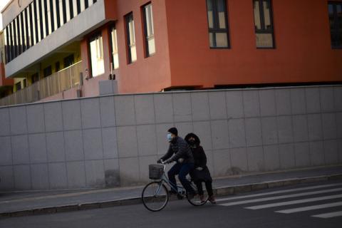 A man wearing a face mask rides a bicycle with a passenger on the back, as the country is hit by an outbreak of the novel coronavirus, on a street in Beijing, China, February 18, 2020. PHOTO BY REUTERS/Tingshu Wang