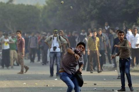 Members of the Muslim Brotherhood and supporters of ousted Egyptian President Mohamed Mursi, throw stones, as riot police fired tear gas to stop them marching towards Rabaa al-Adaweya square, in front of Al-Azhar University in Cairo