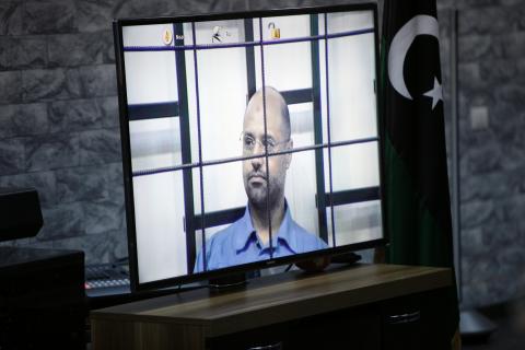 Saif al-Islam Gaddafi, son of deposed leader Muammar Gaddafi, is seen on a screen via video-link in a courtroom in Tripoli as he attends a hearing behind bars in a courtroom in Zintan