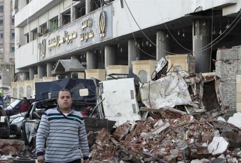 A man walks near debris after an explosion near a security building in Egypt's Nile Delta town of Dakahlyia, about 120 km (75 miles) northeast of Cairo