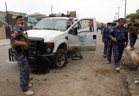 Iraqi security forces inspect the site of a suicide bombing outside a polling station in Kirkuk