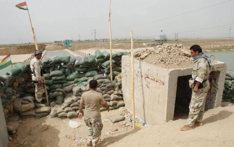 Members of the Kurdish security forces stand guard against Islamic State militants (background), behind sandbags on the Mullah Abdullah bridge in southern Kirkuk