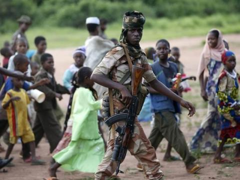 An armed Seleka soldier walks with children from the Peul tribe in the town of Molemi June 4, 2014. Peul cattle herders are mostly Muslims and they are often attacked by "anti-balaka" Christian militia. PHOTO BY REUTERS/Goran Tomasevic