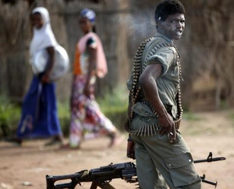 A Seleka soldier smokes as he carries his gun in front of Peul tribeswomen in the town of Molemi, June 4, 2014. PHOTO BY REUTERS/Goran Tomasevic