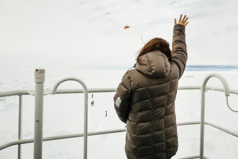 Nicole De Losa, a passenger on board the MV Akademik Shokalskiy waves to a helicopter sent from the Chinese icebreaker Xue Long (Snow Dragon) to assess ice conditions around the Russian Ship, in East Antarctica