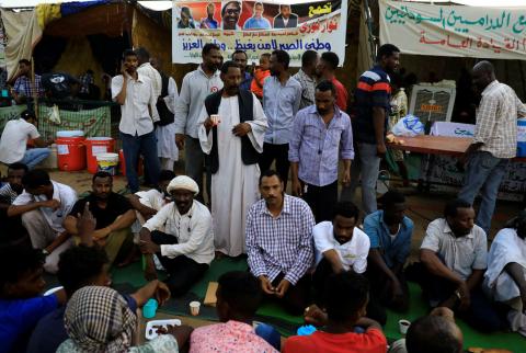 Ahmed Rabie (sitting, 5th L), a member of the Sudanese Professionals Association (SPA), waits to break his fast with his friends during the Muslim fasting month of Ramadan in front of the Defence Ministry compound in Khartoum, Sudan, May 7, 2019. PHOTO BY REUTERS/Umit Bektas