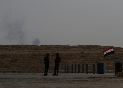 Smoke rises as Syrian army soldiers stand near a checkpoint in Deir al-Zor, Syria, September 21, 2017. REUTERS/Omar Sanadiki