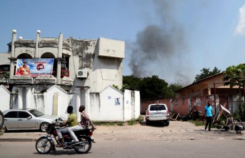 A motorcyclist rides near smoke billowing from fire at the independent national electoral commission's (CENI) warehouse in Kinshasa, Democratic Republic of Congo, December 13, 2018. PHOTO BY REUTERS/Olivia Acland