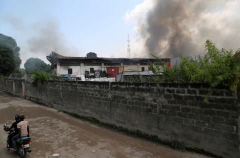 A motorcyclist rides near smoke billowing from fire at the independent national electoral commission's (CENI) warehouse in Kinshasa, Democratic Republic of Congo, December 13, 2018. PHOTO BY REUTERS/Olivia Acland