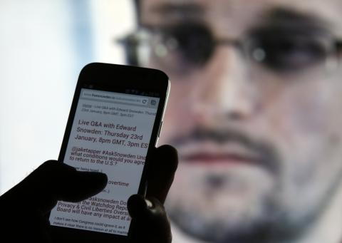 A man uses his cell phone to read updates about former U.S. spy agency contractor Edward Snowden answering users' questions on Twitter in this photo illustration, in Sarajevo