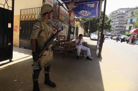 A soldier and policeman wait for voters at a polling station in the El Sayda Zeinab area on the third day of voting in the Egyptian presidential election in Cairo