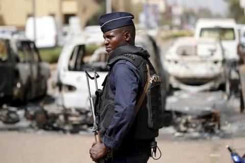 A soldier stands guard in front of burned cars across the street from Splendid Hotel in Ouagadougou, Burkina Faso, January 17, 2016. PHOTO BY REUTERS/Joe Penney