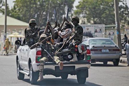 Soldiers and people carrying machetes ride on the back of a vehicle along a street in Gombe, January 30, 2015. PHOTO BY REUTERS/ Afolabi Sotunde