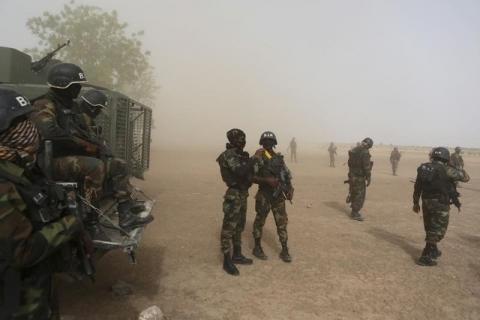 Cameroonian soldiers from the Rapid Intervention Brigade stand guard amidst dust kicked up by a helicopter in Kolofata, Cameroon, March 16, 2016. PHOTO BY REUTERS