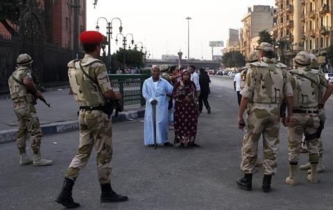 Pedestrians look as the Egyptian army soldiers divert traffic away from the front of the Egyptian museum in Cairo