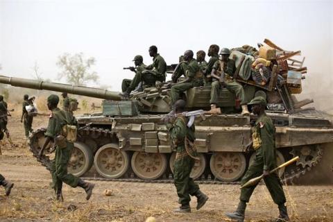 South Sudanese soldiers walk alongside a tank as they withdraw from the town of Jau, at the disputed border with Sudan