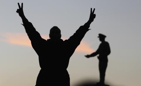 A supporter of the constitution gestures in front of a statue of Egypt's former Army Chief of Staff Abdel Moneim Riad near Tahrir square, during the final stage of a referendum on Egypt's new constitution in Cairo