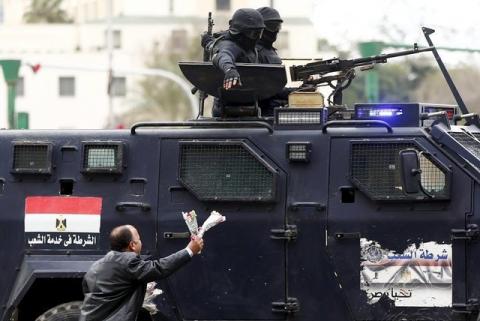 A pro-government protester runs and tries to give flowers to members of security forces during the fifth anniversary of the uprising that ended the 30-year reign of Hosni Mubarak in Cairo, Egypt, January 25, 2016. PHOTO BY REUTERS/Amr Abdallah Dalsh