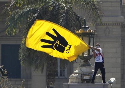 A student supporter of the Muslim Brotherhood and ousted Egyptian President Mohamed Mursi waves the yellow flag bearing the four-fingered Rabaa sign during a demonstration outside Cairo University, May 14, 2014. PHOTO BY REUTERS/Mohamed Abd El Ghany