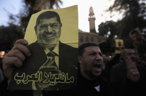 A member of the Muslim Brotherhood and supporter of ousted Egyptian President Mohamed Mursi shouts slogans against the military and interior ministry with his poster while gesturing with four fingers, in front of Al Rayyan mosque after Friday prayer