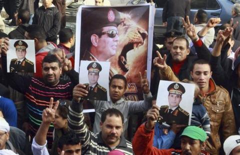 Supporters of the Egyptian Army and Army chief General Abdel Fattah al-Sisi shout slogans with posters of Sisi against ousted Egyptian President Mohamed Mursi and members of the Muslim Brotherhood, in front of a damaged building of a court complex after an explosion in Imbaba, north of Cairo