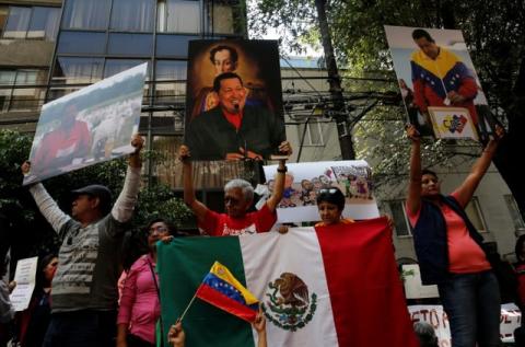 Supporters of Venezuelan President Nicolas Maduro hold up pictures of Venezuela's late president Hugo Chavez, during an event in favor of Venezuela's Constituent Assembly election, outside Venezuela's embassy in Mexico City, Mexico, July 30, 2017. PHOTO BY REUTERS/Henry Romero