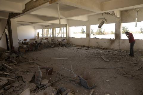 A teacher stands inside a damaged classroom after the building was bombed by a Libyan warplane at a university in Benghazi